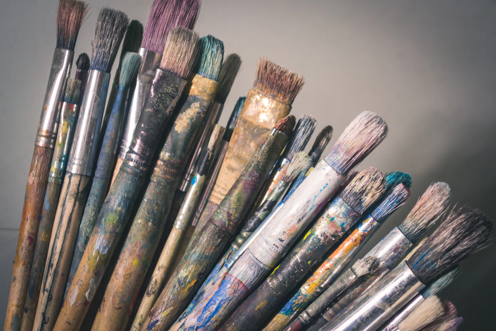 A fan of well-used artist&rsquo;s brushes, their handles stained with dried paint.
